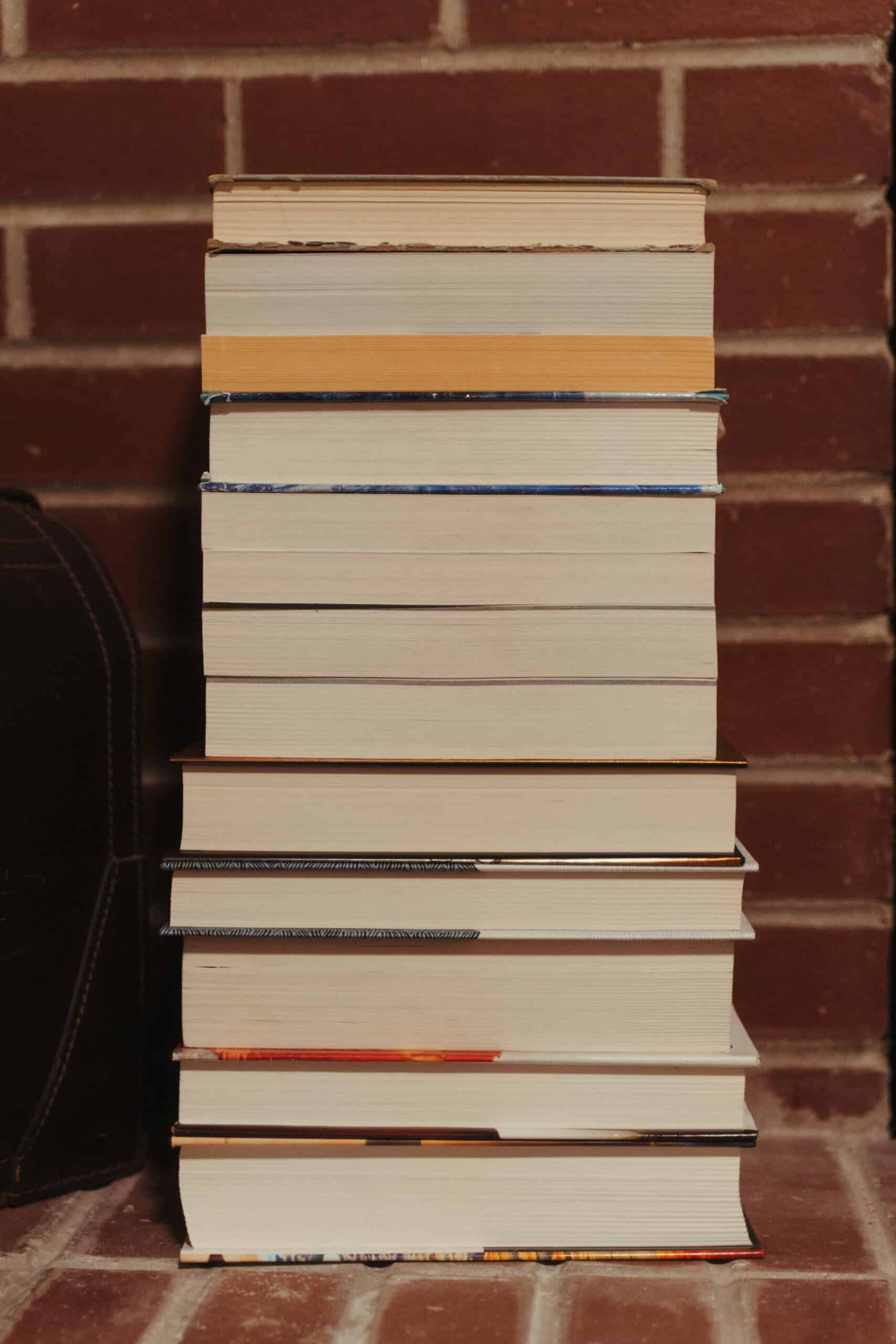 Tall stack of books against a brick wall, ready for reading.